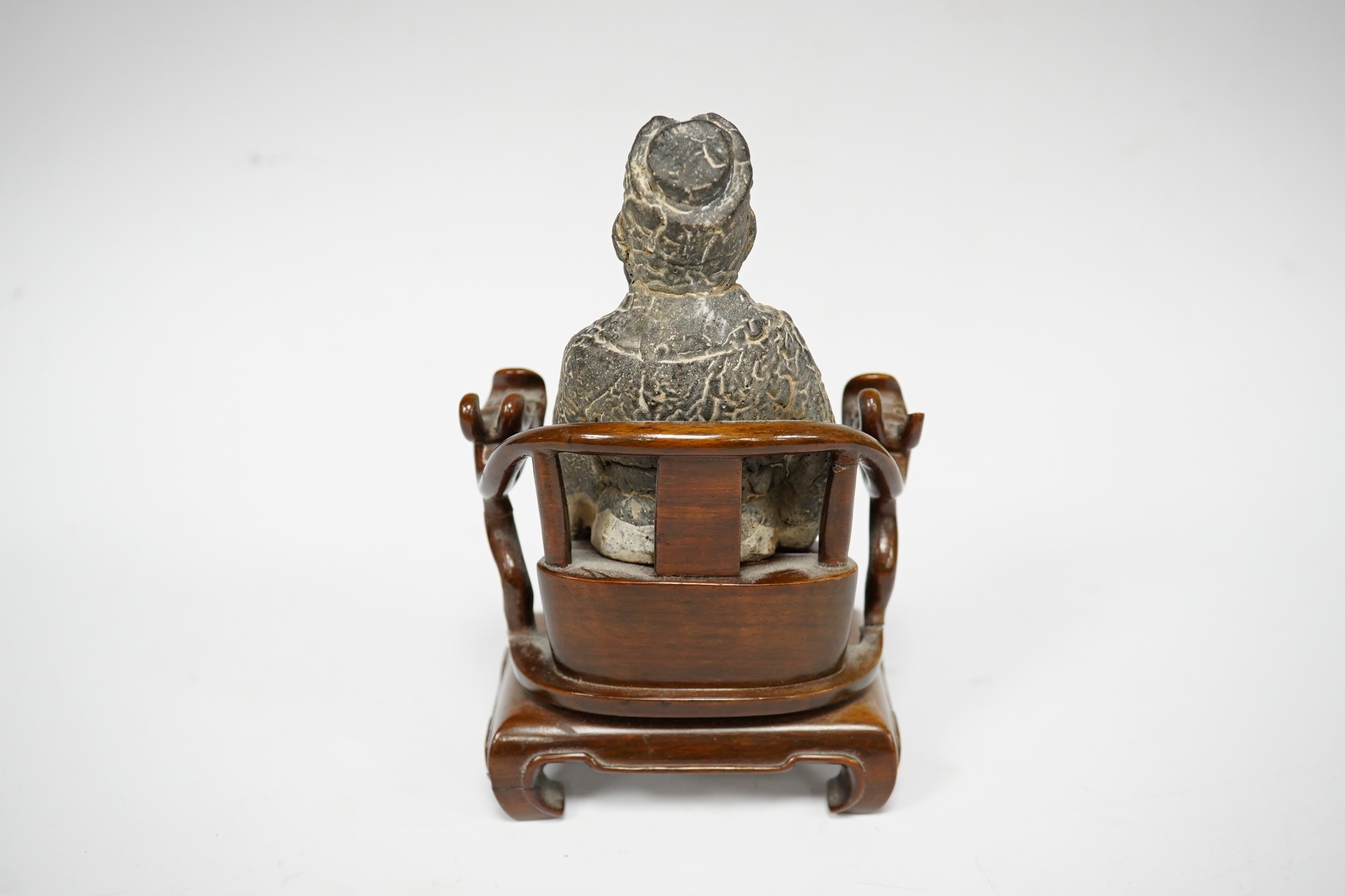 A Chinese grey pottery seated figure of a God, possibly Ming dynasty, seated on a later wood throne (with receipt of purchase from C C Tih Gallery, Hong Kong, 1968), 15cm high. Condition - fair